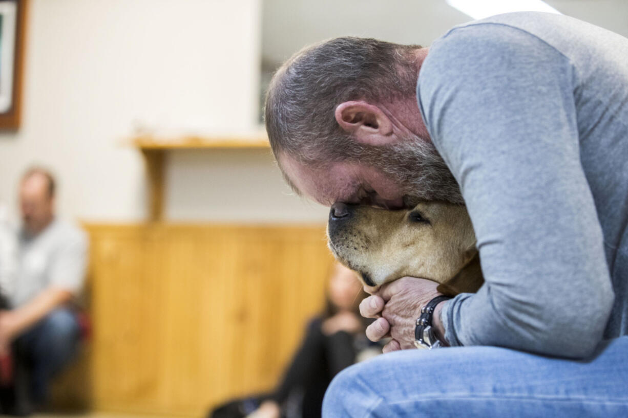 Doug Monda, a retired police officer, shares a moment with Ash, a yellow Labrador retriever and his new service dog, during a Mutts with a Mission graduation ceremony Friday in Virginia Beach, Va. Ash was one of five new graduates.