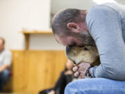 Doug Monda, a retired police officer, shares a moment with Ash, a yellow Labrador retriever and his new service dog, during a Mutts with a Mission graduation ceremony Friday in Virginia Beach, Va. Ash was one of five new graduates.