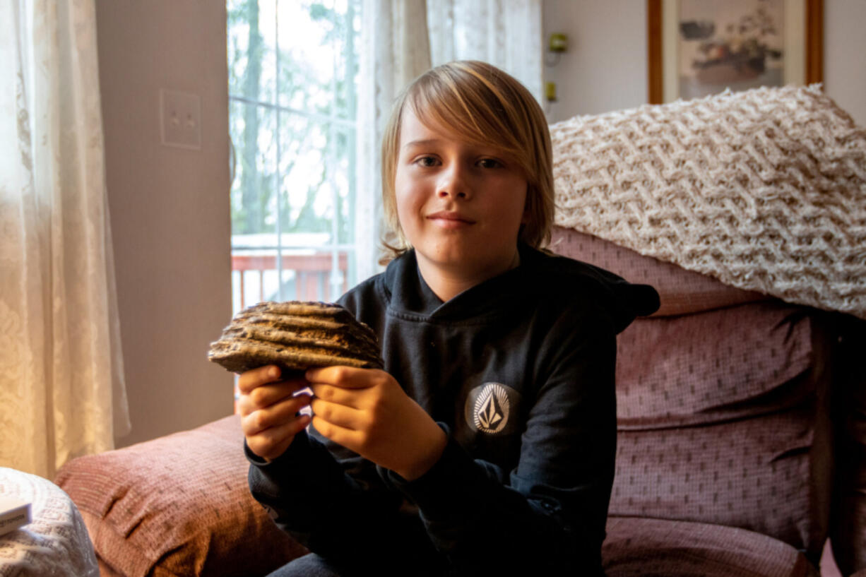 Jeremiah Longbrake, 9, holds the mammoth tooth he found in his grandmother???s backyard while sitting Thursday inside the Winston home.