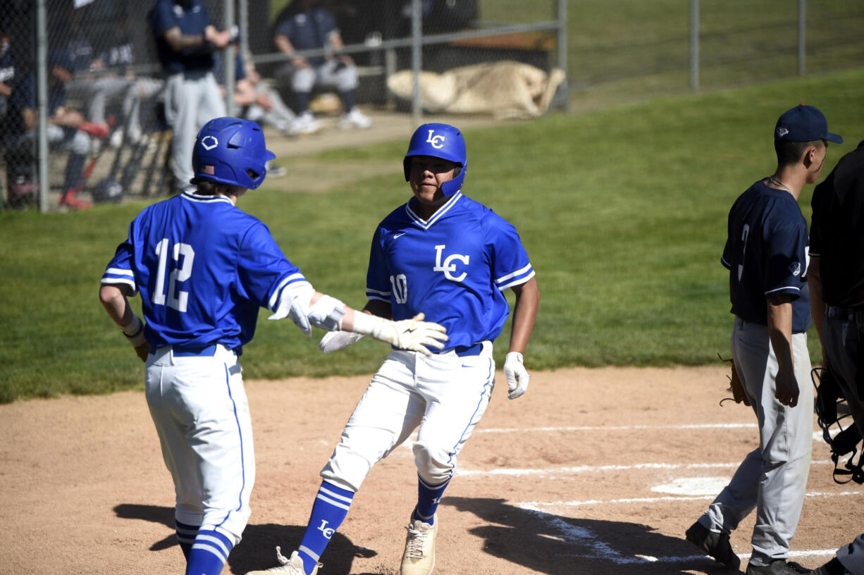 La Center’s Caden Taylor (12) greets Alex Mora (10) after scoring a run in the first inning of a Trico League baseball game on Friday, April 28, 2023, at La Center High School.