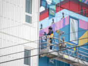 Portland-based artist Christian T?llez works on a mural Tuesday at the Fourth Plain Community Commons building. The mural's design is a tribute to the community's diversity, according to an Instagram post by the city of Vancouver.