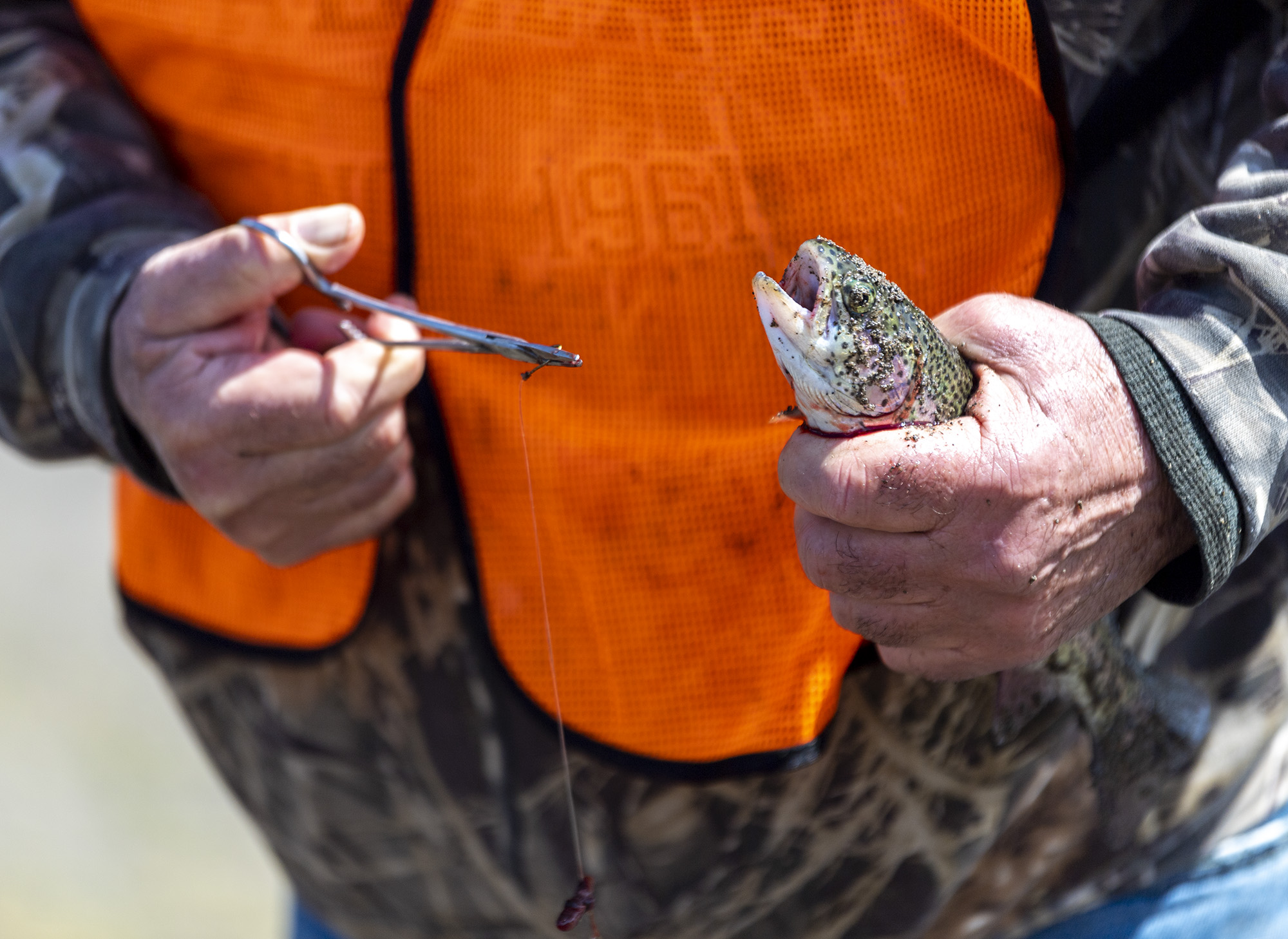 Volunteer fishing guide Greg Glass takes the hook out of a mouth of a rainbow trout Friday, April 14, 2023, during the Klineline Kids Fishing Derby at Klineline Pond. The two-day event attracts about 3,000 kids and their families, according to the event website.