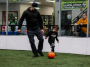 Brett Seifried of Ridgefield kicks a soccer ball with his son, Archer, 5, at Salmon Creek Indoor Sports Arena on a recent Sunday. Archer participates in Salmon Creek TOPSoccer, an inclusive team for kids with disabilities. Archer, who has cerebral palsy, can control his body much better after undergoing selective dorsal rhizotomy surgery at Seattle Children's Hospital in 2022.