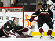 Seattle Kraken left wing Jared McCann (19) has his shot blocked by Arizona Coyotes goaltender Ivan Prosvetov (50) as Coyotes left wing Matias Maccelli, second from right, looks on during the first period of an NHL hockey game Monday, April 10, 2023, in Tempe, Ariz. (AP Photo/Ross D.