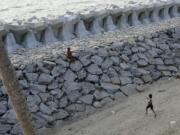 Kids play on a newly build sea wall in Kochi, Kerala state, India, March 4, 2023. Tens of millions of people in India live along coastlines and thus are exposed to major weather events. One common adaptation technique, in India and other countries hit hard by rising seas and oceanic storms, is to build sea walls.