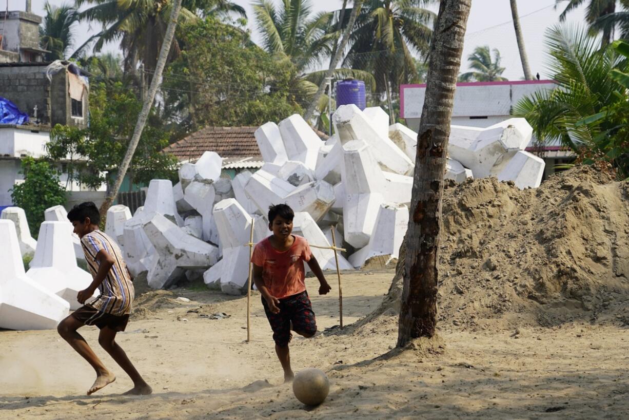 Children play soccer near a pile of tetrapods that will be part of a new sea wall in Kochi, Kerala state, India, March 4, 2023. Tens of millions of people in India live along coastlines and thus are exposed to major weather events.