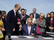 Washington Gov. Jay Inslee hands a pen to Rep. Drew Hansen, D-Bainbridge Island, left, after signing House Bill 1469, which shields abortion and gender-affirming care patients and providers from prosecution by out-of-state authorities and prevents cooperation with investigations, Thursday, April 27, 2023, at the University of Washington's Hans Rosling Center for Population Health in Seattle.