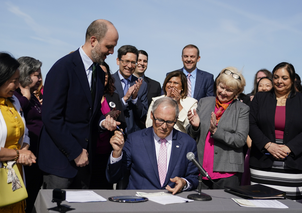 Washington Gov. Jay Inslee hands a pen to Rep. Drew Hansen, D-Bainbridge Island, left, after signing House Bill 1469, which shields abortion and gender-affirming care patients and providers from prosecution by out-of-state authorities and prevents cooperation with investigations, Thursday, April 27, 2023, at the University of Washington's Hans Rosling Center for Population Health in Seattle.