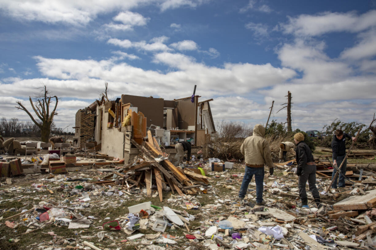 Family and neighbors look through debris on Ed Whestine's farm southwest of Wellman, Iowa on Saturday, April 1, 2023. Storms that dropped possibly dozens of tornadoes killed multiple people in small towns and big cities across the South and Midwest, tearing a path through the Arkansas capital, collapsing the roof of a packed concert venue in Illinois, and stunning people throughout the region Saturday with the damage's scope.