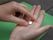 FILE - A patient prepares to take the first of two pills for a medication abortion during a visit to a clinic in Kansas City, Kan., on Wednesday, Oct. 12, 2022. Some abortion clinics are fielding lots of calls from patients since a Friday, April 7, 2023 court ruling threatened the availability of a main drug used in medication abortion, mifepristone. Patients are concerned about whether they can still get the care they need.