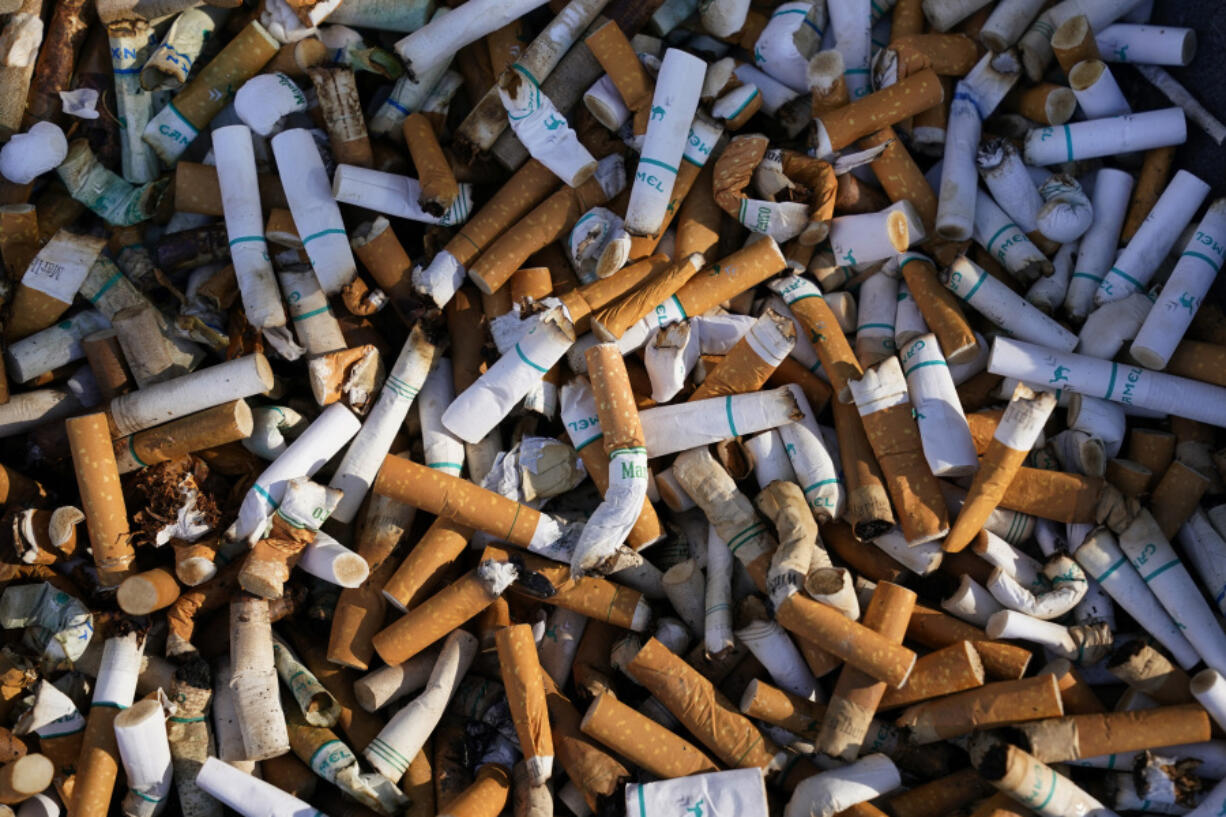 FILE - Cigarette butts fill a smoking receptacle outside a federal building in Washington, Thursday, April 15, 2021. According to government survey data released Thursday, April 27, 2023, U.S. adults are smoking less. Cigarette smoking dropped to another new all-time low in 2022, with 1 in 9 adults saying they were current smokers. Meanwhile, e-cigarette use rose, to about 1 in 17 adults. (AP Photo/J.