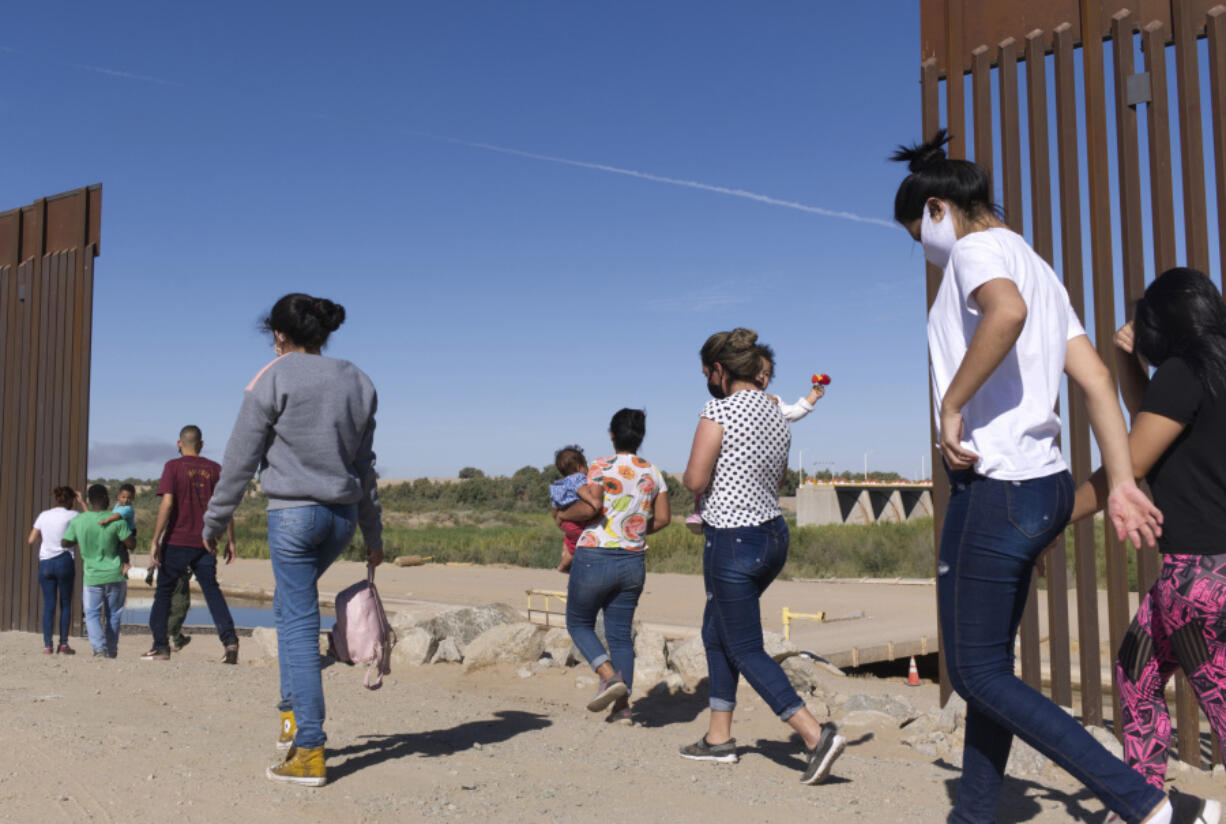 FILE - A group of Brazilian migrants make their way around a gap in the U.S.-Mexico border in Yuma, Ariz., seeking asylum in the U.S. after crossing over from Mexico, June 8, 2021. The U.S. Department of Homeland Security says migrants entering the country illegally will be screened by asylum officers while in custody under a limited experiment that provides them access to legal counsel.