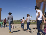 FILE - A group of Brazilian migrants make their way around a gap in the U.S.-Mexico border in Yuma, Ariz., seeking asylum in the U.S. after crossing over from Mexico, June 8, 2021. The U.S. Department of Homeland Security says migrants entering the country illegally will be screened by asylum officers while in custody under a limited experiment that provides them access to legal counsel.