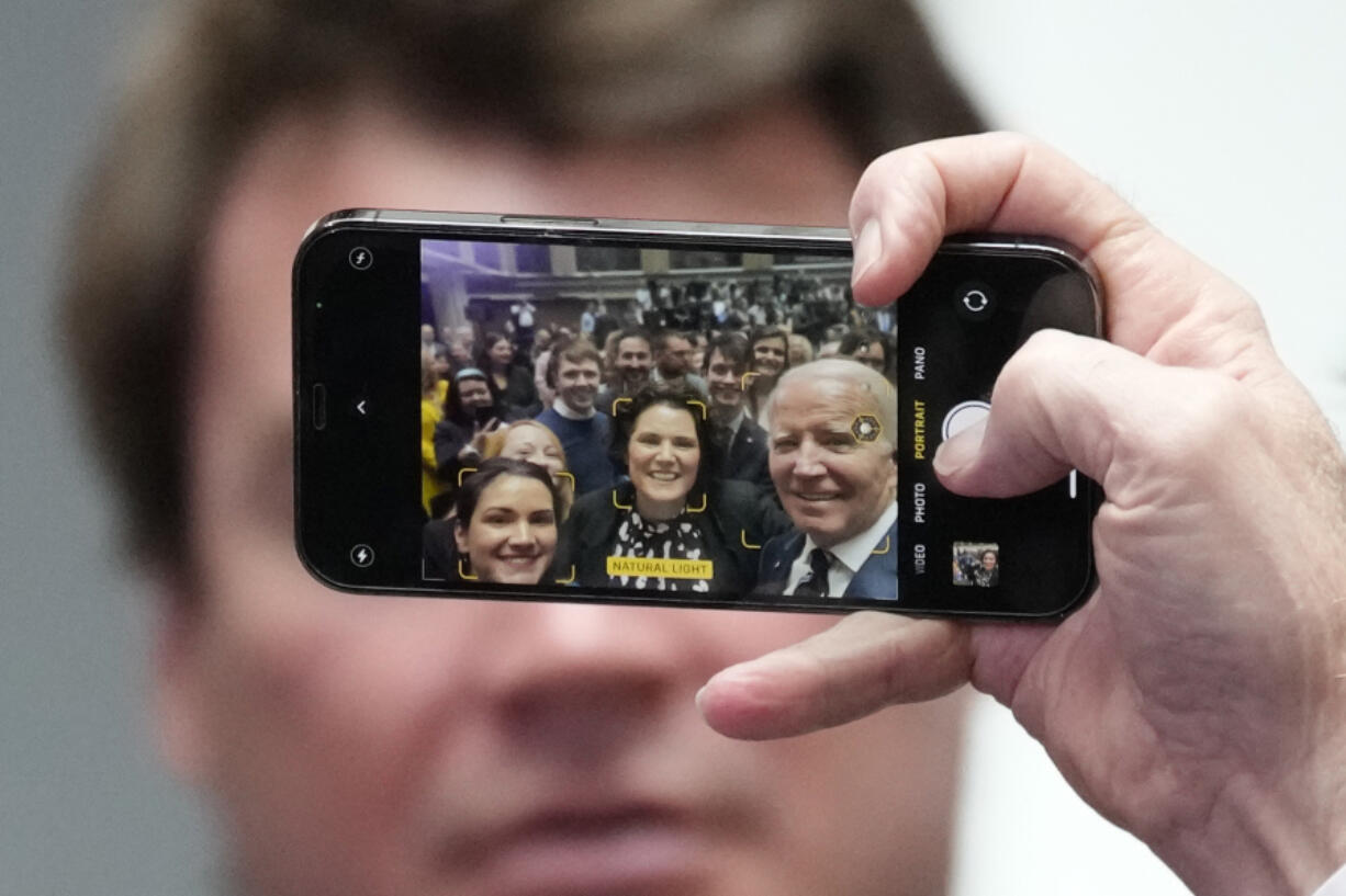 President Joe Biden holds a cellphone as he takes a picture with a members of the audience after making a speech about Northern Ireland's vast economic potential at the Ulster University's new campus in Belfast, Northern Ireland, Wednesday, April 12, 2023. President Biden is in Northern Ireland on Wednesday to participate in marking the 25th anniversary of the Good Friday Agreement, which brought peace to this part of the United Kingdom, as a new political crisis tests the strength of that peace.