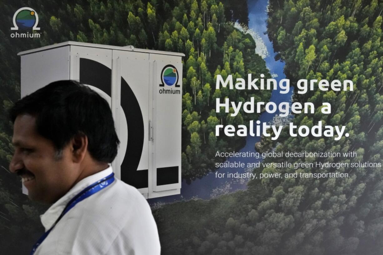 An employee walks past a large picture displayed at the Ohmium manufacturing facility in Chikkaballapur, outside Bengaluru, India, Tuesday, April 25, 2023. The company announced Wednesday, April 26, it has raised $250 million to expand production of machines that can make clean hydrogen and displace fossil fuels. Ohmium's role is to make electrolyzers, the devices that take water and split it into hydrogen and oxygen.