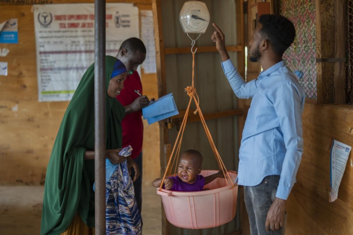 FILE - A child is weighed at a camp for displaced people amid a drought on the outskirts of Dollow, Somalia, Sept. 19, 2022.  Looking back at 2022's weather with months of analysis, the World Meteorological Organization says last year really was as bad as it seemed.