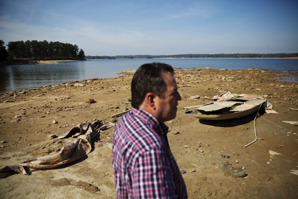 FILE - A sunken boat is exposed by receding water levels on Lake Lanier as U.S. Army Corps of Engineers Natural Resources Manager Nick Baggett looks on in Flowery Branch, Ga., Oct. 26, 2016. A new study finds that climate change is making droughts faster and more furious -- and especially one fast-moving kind of drought that can take farmers by surprise.