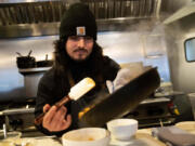 Santos Enrique Camara, 27, who dropped out of Shoreline Community College at age 19 in 2015, prepares food at Capers + Olives Friday, March 24, 2023, in Everett, Wash. where he works as a sous-chef and cook. Advocates for community colleges defend them as the underdogs of America's higher education system, left to serve the students who need the most support but without the money to provide it. Critics contend this has become an excuse for poor success rates and for the kind of faceless bureaucracies that ultimately led Camara to drop out after two semesters.