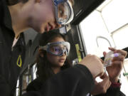 Students Siari Rodriguez, left, and Crystal Baker use a pH strip to test the pH of common substances in their Chemistry 121 class at Everett Community College on Friday, March 10, 2023. Students who need extra help in subjects struggle to learn if the content is taught in an abstract, isolated manner, educators say. That's why I-BEST programs feature two teachers in the classroom: one provides job training and the other teaches basic skills in reading, math or English language.