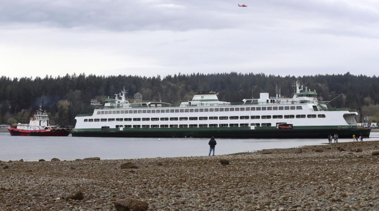 People stand on the shore while looking at the Walla Walla passenger ferry after it ran aground near Bainbridge Island west of Seattle on Saturday, April 15, 2023. (Meegan M.