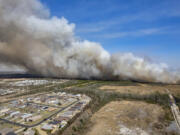 FILE - A fast-moving wildfire looms over homes outside of Panama City, Fla., March 4, 2022. Florida state and federal officials said Thursday, April 6, 2023, that the threat of wildfires is growing in Florida over the coming weeks as more than half the state is experiencing severe to extreme drought conditions likely to persist until rainy season resumes around mid-May.