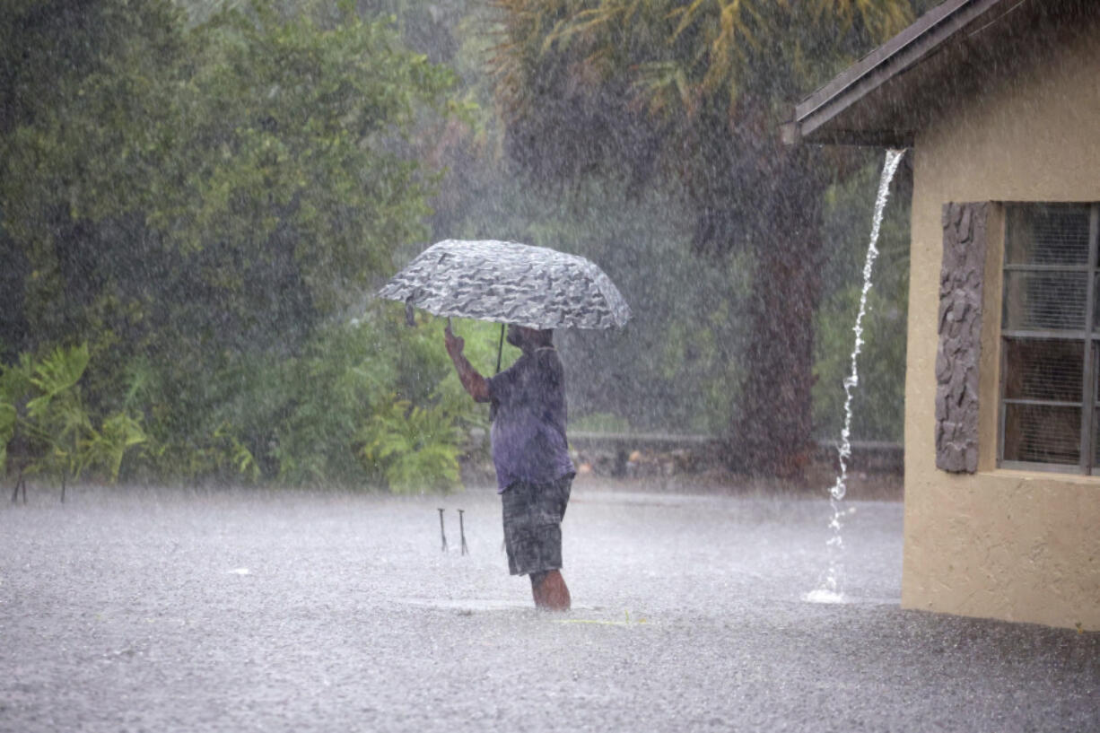 A man stops to take pictures of his flooded neighborhood along SW 3rd Street and SW 4th Ave in Dania Beach, Fla., on Wednesday, April 12, 2023.