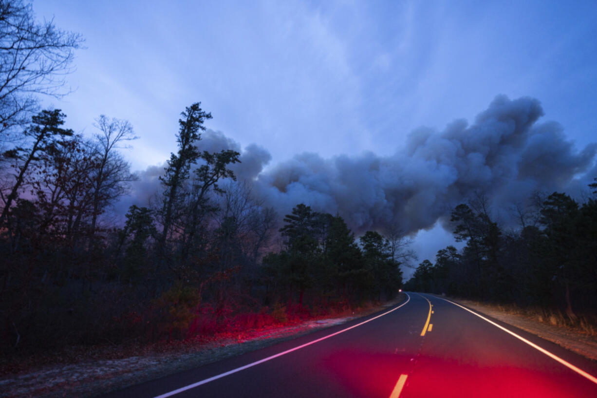 In this photo provided by the New Jersey Department of Environmental Protection, a massive 2,500-acre forest fire burns in Ocean County, N.J., early Wednesday, April 12, 2023, as firefighters battle the blaze. The fire started late Tuesday, April 11, and is burning across some 2,500 acres (about 1,000 hectares).