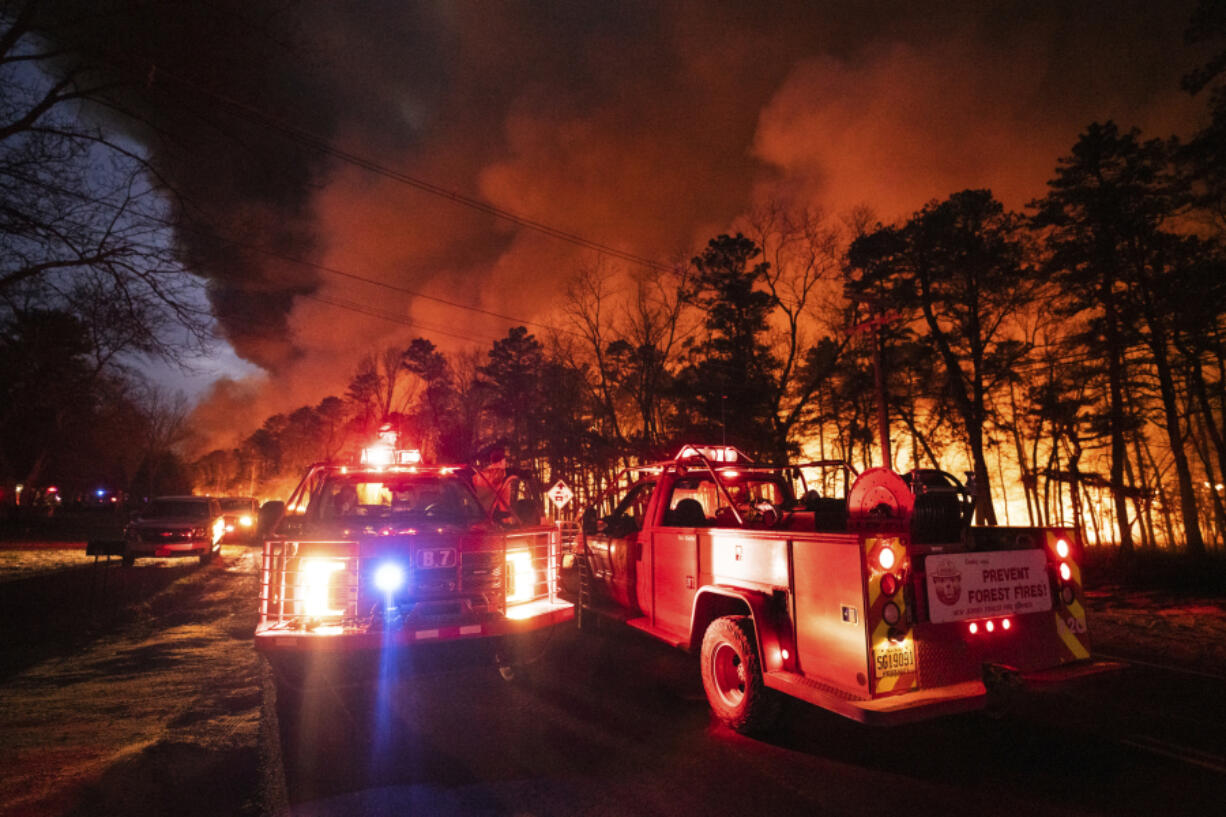 In this photo provided by the New Jersey Department of Environmental Protection, a massive 2,500-acre forest fire burns in Ocean County, N.J., early Wednesday, April 12, 2023, as firefighters battle the blaze. The fire started late Tuesday, April 11, and is burning across some 2,500 acres.  (about 1,000 hectares).