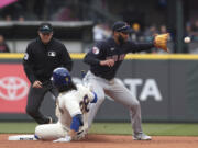 Seattle Mariners' Eugenio Suarez, front left, is safe at second base as Cleveland Guardians shortstop Amed Rosario, right, receives the throw during the fifth inning of a baseball game, Sunday, April 2, 2023, in Seattle.