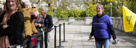 Sara Jones, right, with "We the People Against Communism," yells at guests lining up to enter the Capitol while she protests ahead of the signing of firearms regulation bills by Washington Gov. Jay Inslee, Tuesday, April 25, 2023, in Olympia, Wash.