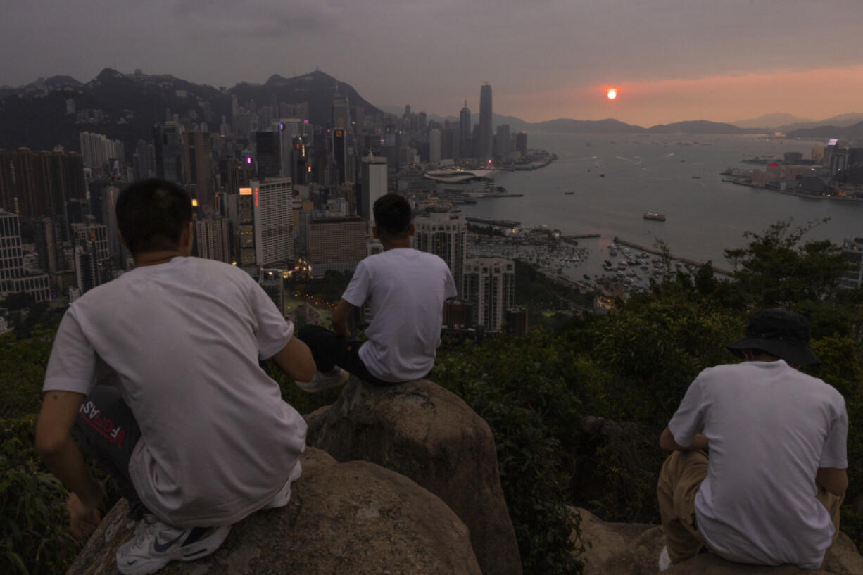 FILE - Mainland Chinese tourists look at sunset from a hill in Hong Kong, April 26, 2023. Living in Hong Kong today means juggling contradictory feelings. In 20 interviews, many said that when they focus on business indicators and everyday life, they see a recovery gathering pace after years of travel restrictions. But when it comes to anything political, the openness and freedoms that were once hallmarks of the Chinese-ruled former British colony seem permanently gone.