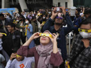 People use protective glasses to watch solar eclipse in Jakarta, Indonesia, Thursday, April 20, 2023. A rare solar eclipse will cross over remote parts of Australia, Indonesia and East Timor on Thursday.