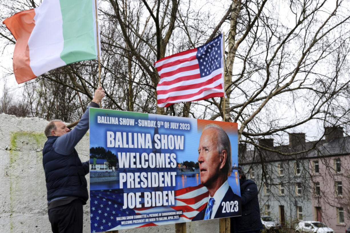 Ray Clarke, left, and Eddie Ruane put up flags in Ballina, Ireland, Tuesday, April, 4, 2023. Excitement is building in Ballina, a small Irish town that was home to some of President Joe Biden's ancestors. Biden is scheduled to visit the town next week, part of a four-day trip to Ireland and neighboring Northern Ireland.