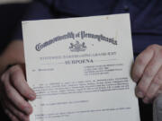 Martin Haugh, a former Jehovah's Witnesses elder and father of a sexual abuse victim, holds a subpoena, dated in 2019, ordering him to testify in front of a Pennsylvania grand jury, shown on Wednesday, April 12, 2023, in York Haven, Pa. The four-year grand jury investigation overseen by the attorney general's office has produced charges of child sexual abuse against nine men, all affiliated with the faith.