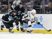 Los Angeles Kings right wing Viktor Arvidsson (33) and Seattle Kraken right wing Oliver Bjorkstrand (22) and defenseman Jamie Oleksiak (24) compete for the puck during the second period of an NHL hockey game Saturday, April 1, 2023, in Seattle.