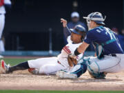 Cleveland Guardians' Jose Ramirez, left, scores the game winning run past Seattle Mariners catcher Cal Raleigh on a fielders choice by Josh Bell during the 12th inning of a baseball game, Sunday, April 9, 2023, in Cleveland.