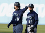 Seattle Mariners' Eugenio Suarez (28) celebrates first base coach Kristopher Negr?n (45) after hitting an RBI single off Cleveland Guardians starting pitcher Cal Quantrill during the first inning of a baseball game Saturday, April 8, 2023, in Cleveland.