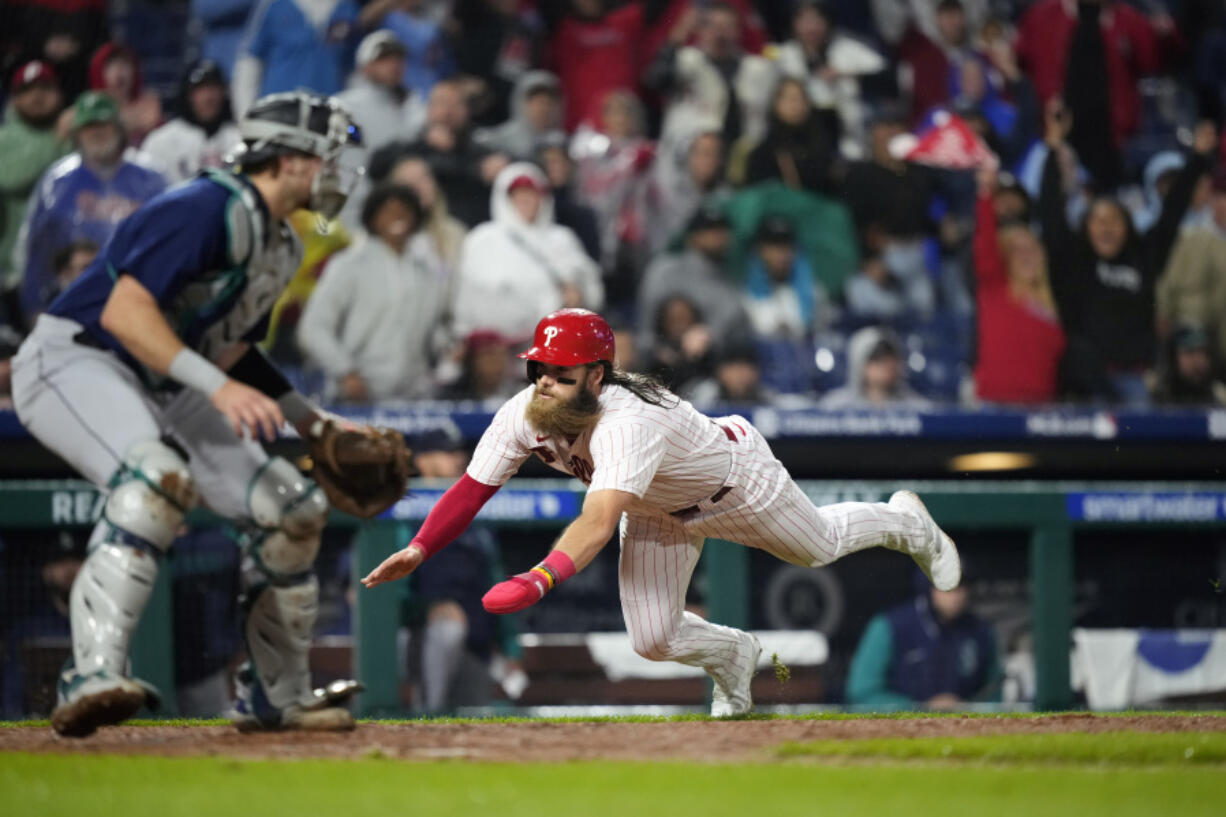 Philadelphia Phillies' Brandon Marsh, right, scores past Seattle Mariners catcher Cal Raleigh on a single by Alec Bohm during the eighth inning of a baseball game, Wednesday, April 26, 2023, in Philadelphia.