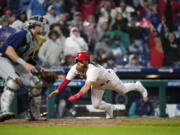 Philadelphia Phillies' Brandon Marsh, right, scores past Seattle Mariners catcher Cal Raleigh on a single by Alec Bohm during the eighth inning of a baseball game, Wednesday, April 26, 2023, in Philadelphia.