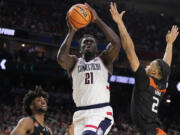 Connecticut forward Adama Sanogo scores past Miami guard Isaiah Wong during the second half of a Final Four college basketball game in the NCAA Tournament on Saturday, April 1, 2023, in Houston.