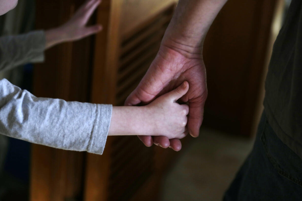 An autistic boy holds the hand of his adoptive father as they prepare to leave for a family outing from their home in Springfield, Mass.