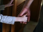 An autistic boy holds the hand of his adoptive father as they prepare to leave for a family outing from their home in Springfield, Mass.