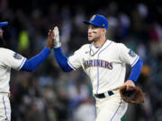 Seattle Mariners' Jarred Kelenic, right, high-fives teammate Teoscar Hernandez, left, as they celebrate a 1-0 win over the Colorado Rockies in a baseball game, Sunday, April 16, 2023, in Seattle. Kelenic drove in the only run of the game, an RBI single in the sixth inning to score Ty France.