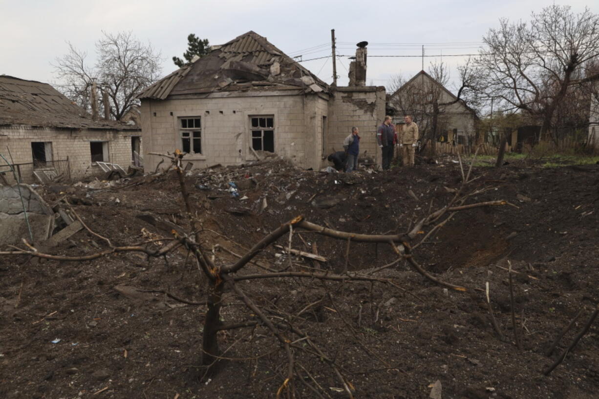 Local residents stand near a crater left by a Russian missile in Zaporizhzhia , Ukraine, Sunday, April 9, 2023. An 11-year old girl and her father were killed in the rocket attack in Zaporizhzhia.