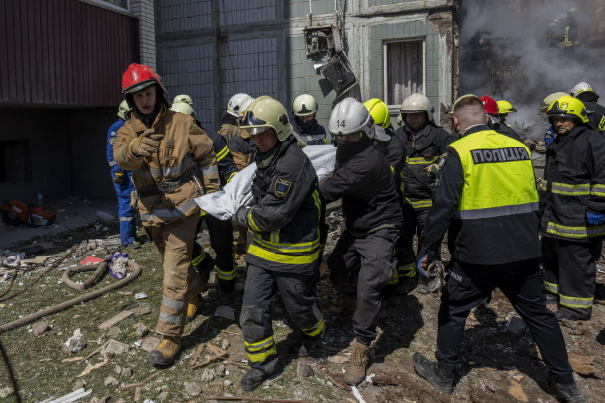 Firefighters carry a body recovered from the rubble of a residential building that was hit during a Russian attack in Uman, central Ukraine, Friday, April 28, 2023.