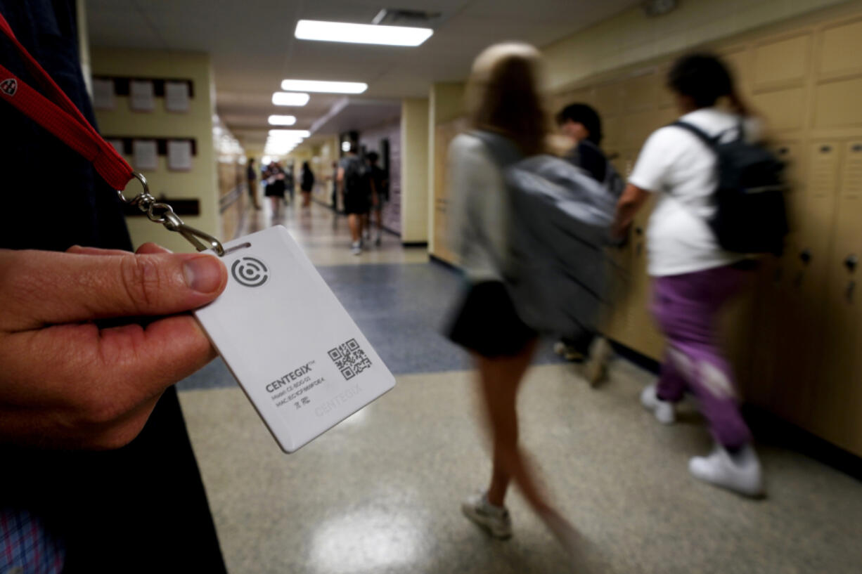 FILE - Brent Kiger, Olathe Public Schools' director of safety service, displays a panic-alert button while students at Olathe South High School rush between classes, Aug. 19, 2022, in Olathe, Kan. The district introduced the buttons, which allow staff to trigger a lockdown that will be announced with flashing strobe lights, a takeover of staff computers and a prerecorded intercom announcement, at the start of this school year as part of $2.1 million plan to make district schools more secure. In the wake of a deadly elementary school shooting in Tennessee earlier this week, state lawmakers across the country are moving forward with school safety measures.