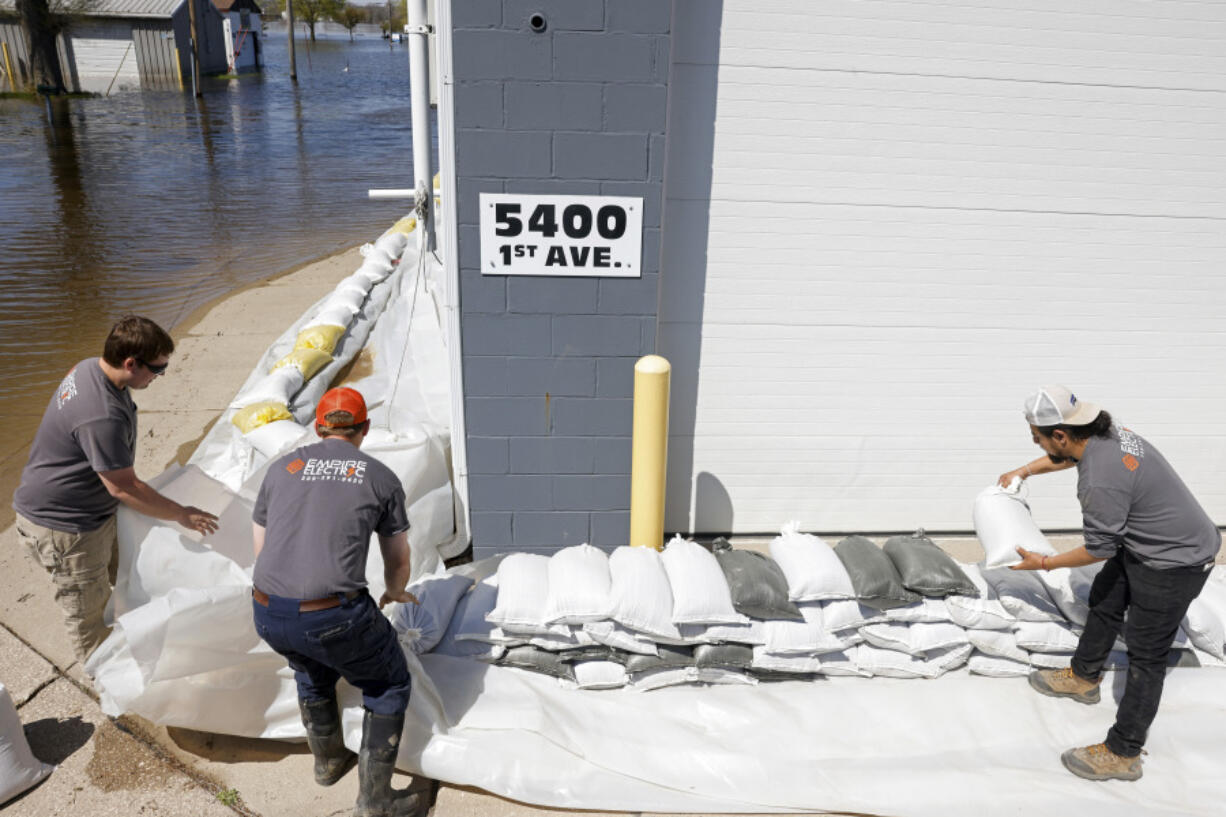 Empire Electric employees place sandbags around the front of the business as the Mississippi River continues to rise on Wednesday in Moline, Ill.