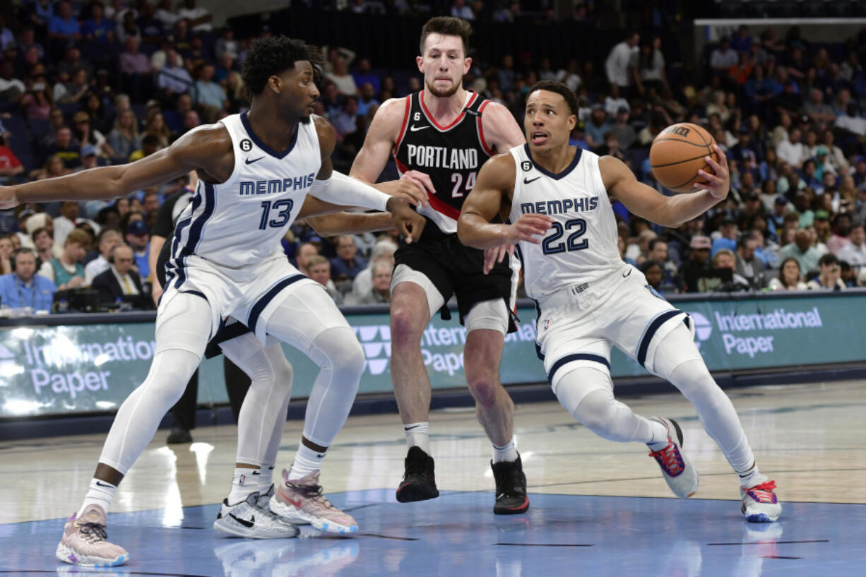 Memphis Grizzlies guard Desmond Bane (22) handles the ball ahead of Portland Trail Blazers forward Drew Eubanks (24) as forward Jaren Jackson Jr. (13) moves for position in the second half of an NBA basketball game Tuesday, April 4, 2023, in Memphis, Tenn.