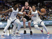 Memphis Grizzlies guard Desmond Bane (22) handles the ball ahead of Portland Trail Blazers forward Drew Eubanks (24) as forward Jaren Jackson Jr. (13) moves for position in the second half of an NBA basketball game Tuesday, April 4, 2023, in Memphis, Tenn.