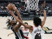 San Antonio Spurs forward Keita Bates-Diop, left, drives to the basket against Portland Trail Blazers forward John Butler Jr. (21) during the second half of an NBA basketball game in Austin, Texas, Thursday, April 6, 2023.